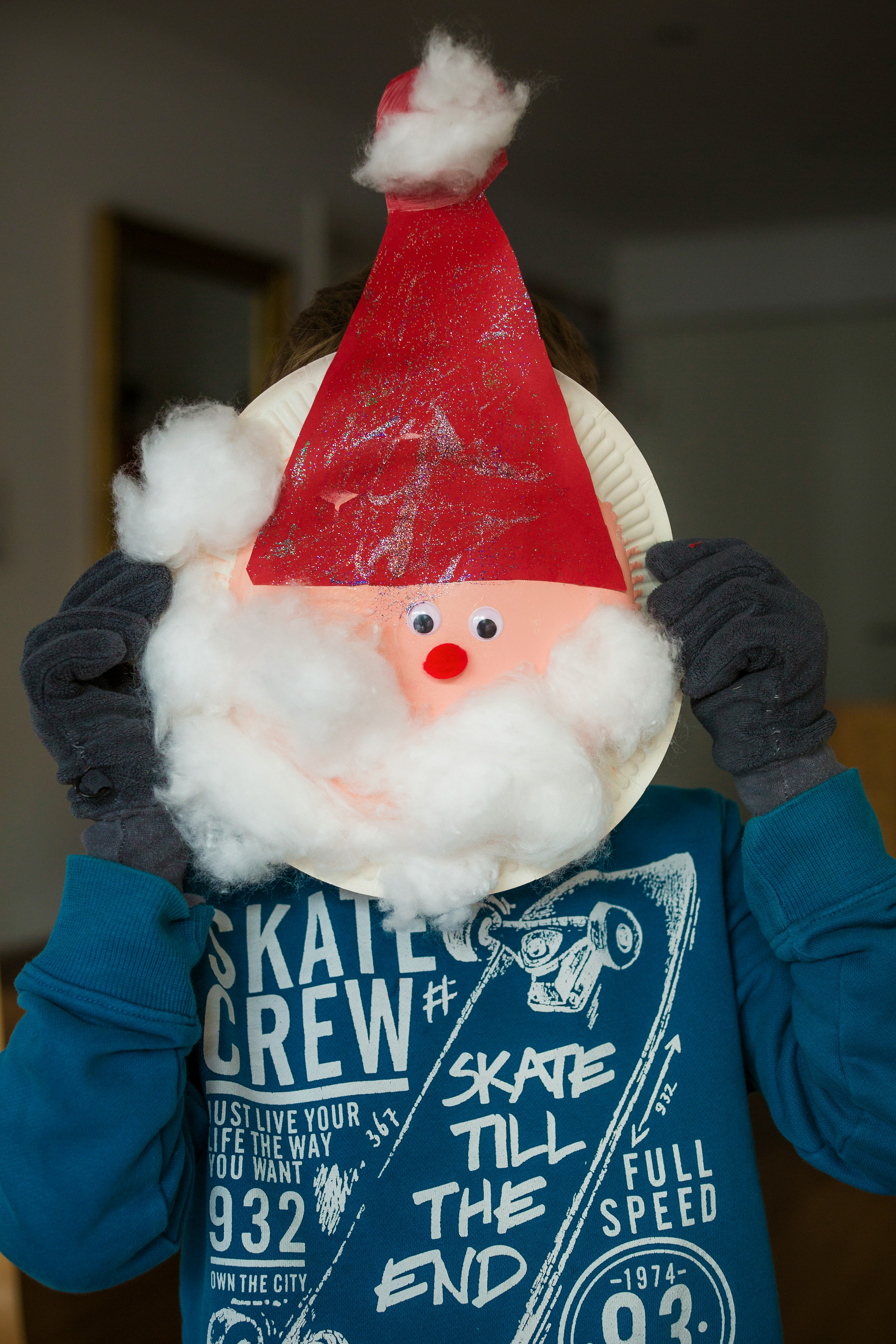 person holding white paper plate with Santa head inside room